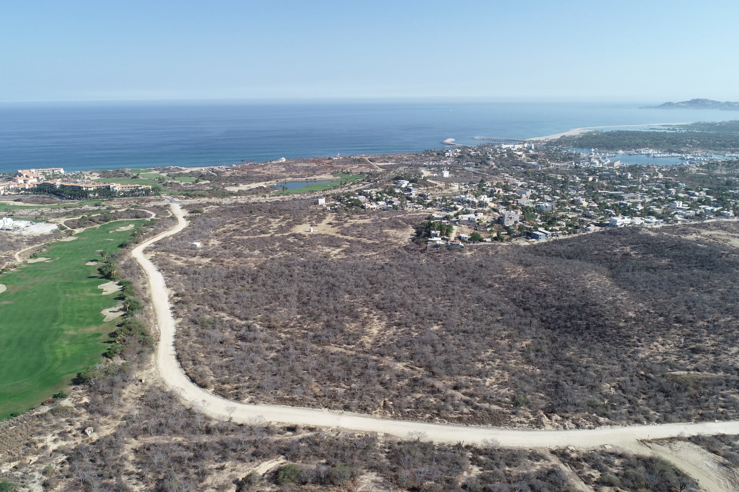 Elevated aerial view of the Vitality Grove site in Puerto Los Cabos with the marina and Pacific Ocean beyond.